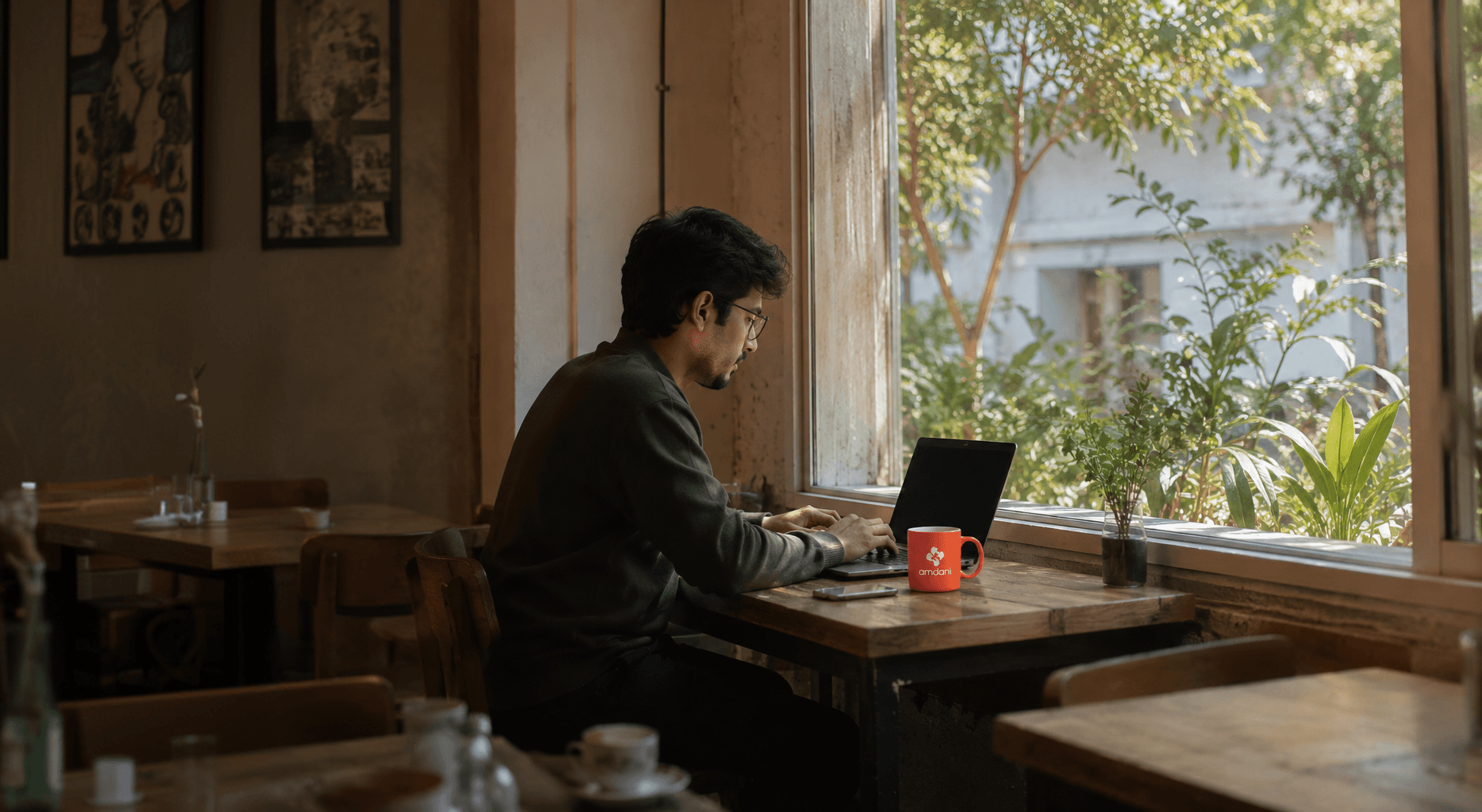 Someone working on a laptop in a sunlit cafe